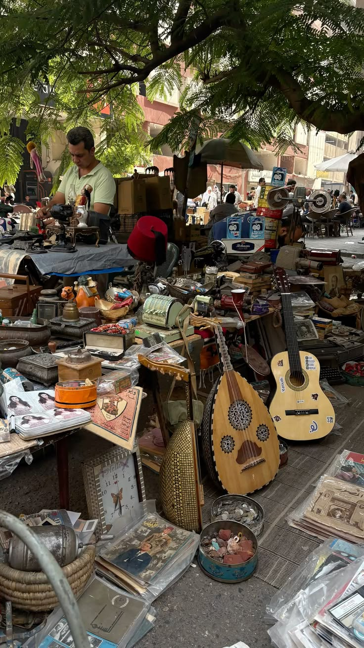 An outdoor antique and flea market stall with instruments, books and vintage goods